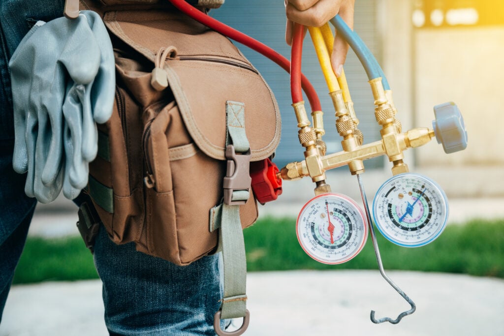 A HVAC technician from JTG Plumbing repairing Air Conditioner. HVAC AC repair services Davis & Weber County. JTG Plumbing Heating & Air
