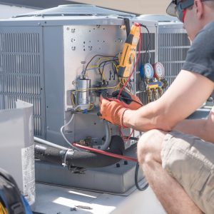 HVAC technician performing spring HVAC maintenance in Northern Utah home. JTG Plumbing Heating & Air